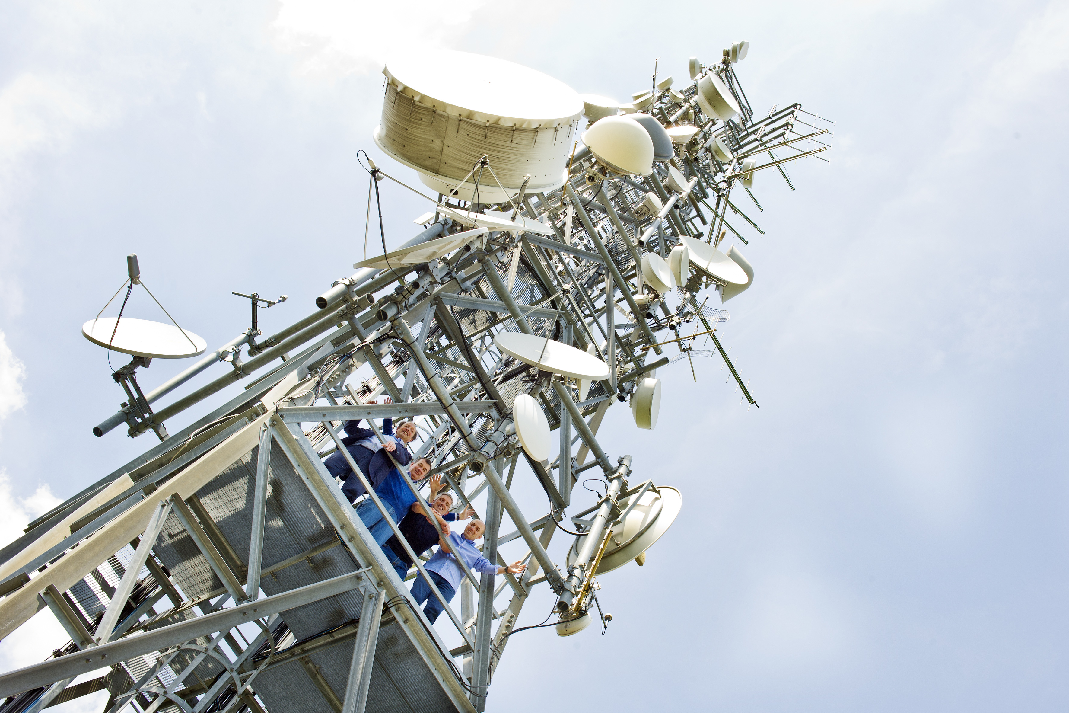 Foto di gruppo davanti a una grande antenna di trasmissione.